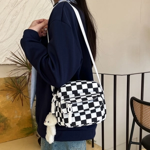 Minimalist checkerboard nylon crossbody bag with white plush bear charm on a wide strap