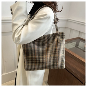 Detail of checkered tote bag with woven shoulder strap in vintage earthy tones