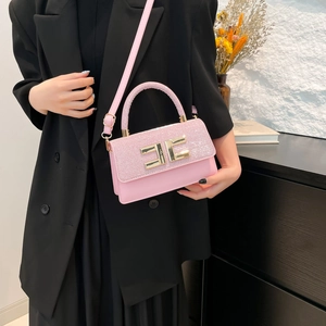 Pink sequin handbag for women with golden buckle and crossbody strap over a black suit