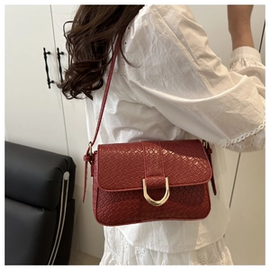 Detail of red snake-pattern leather bag with a golden horseshoe buckle on lace top