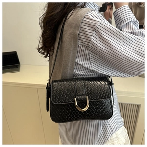 Detail of black woven shoulder bag featuring a prominent gold U-shaped metal buckle clasp