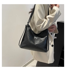 Model wearing a black woven shoulder bag featuring a silver butterfly metal ornament