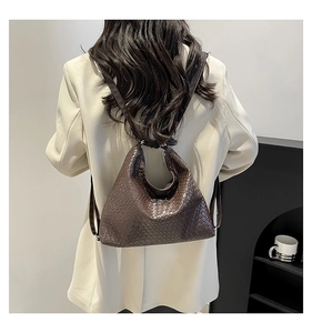 Detail of dark coffee woven textured handbag with triangular structure on model