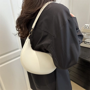 Chic white crescent hobo bag with textured finish shown on shoulder in a street style view
