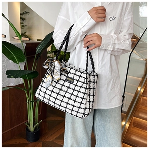 Detail of tweed tote bag featuring woven leather handles and stylish printed silk scarf