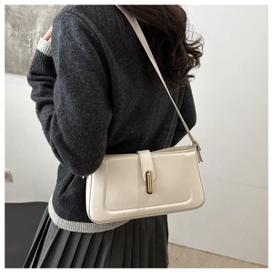 Détail d'un sac sous le bras en cuir beige crème avec boucle dorée élégante porté par un mannequin