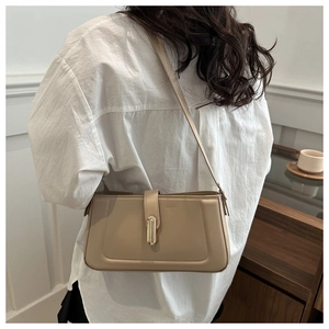 Detail shot of the khaki shoulder bag with gold metal clasp on a minimalist leather surface