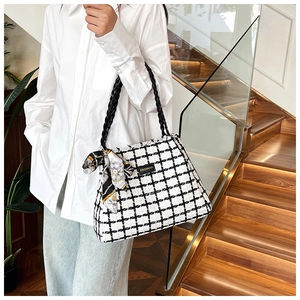 Detail of checkered tweed tote bag with black woven handle and silk scarf on model