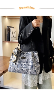 Detail of blue and white striped tote bag with woven handles and silk scarf accent