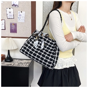 Detail of checkered tweed tote bag featuring decorative silk scarf and woven shoulder strap