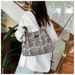Detail of knitted tote bag with geometric pattern, fashion label and silk scarf accessory