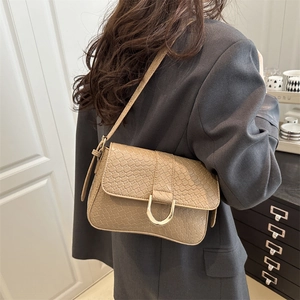 Sac baguette beige en similicuir avec boucle fer à cheval dorée porté par un mannequin