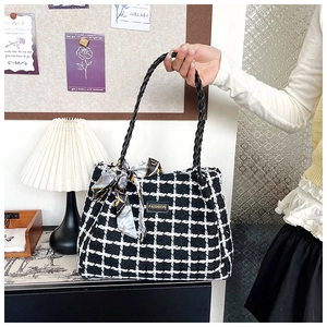 Close-up of black and white tweed tote bag with woven handles and silk scarf detail