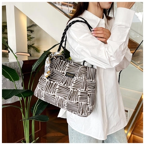 Detail of striped tote bag with woven handles, silk scarf accent, and Fashion label