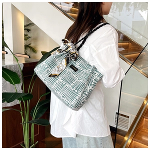Detail of green and white striped tote bag with elegant scarf and fashion label