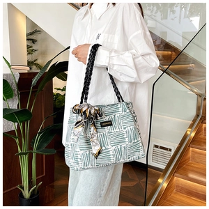 Close-up of green striped canvas tote bag with woven rope handle and silk scarf detail