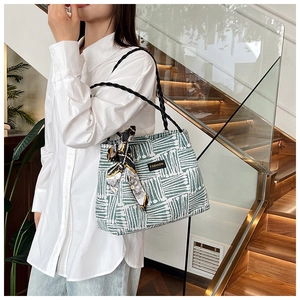 Detail of green and white striped tote bag with fashion label and patterned silk scarf