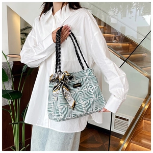 Close-up of green and white woven tote bag with fashion tag and silk scarf detail