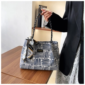Detail of striped tote bag with silk scarf accessory and fashion label on woven fabric