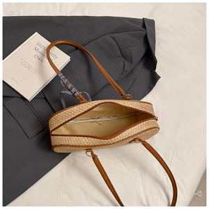 Detail of woven straw bag with leather handle, zipper closure and checkered bow decor