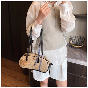 Detail of beige straw cylinder bag with leather straps and cute plush bear charm