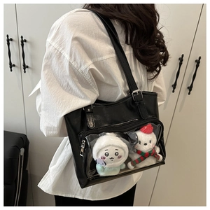 Detail of black leather ita bag with clear window showing plush toys and matte finish