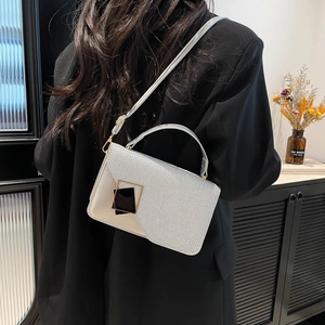 Silver glitter crossbody bag with gold hardware shown on model in black suit jacket