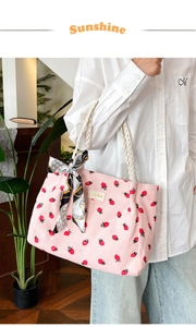 Close-up of pink corduroy tote bag with strawberry print and rope handles with silk scarf