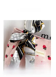 Close-up of pink corduroy tote bag featuring red strawberry prints and a ribbon bow