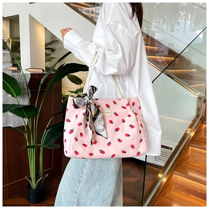 Detail of pink corduroy tote bag with strawberry print and decorative scarf on handle