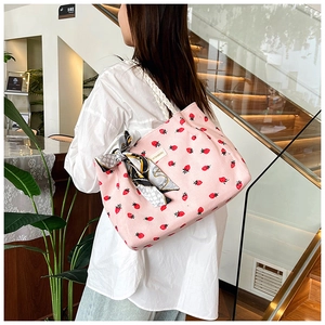 Pink corduroy strawberry tote bag detail with woven rope handles and a patterned scarf