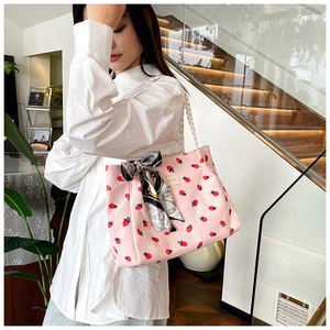 Detailed texture of pink corduroy tote bag with strawberry print and silk scarf decor