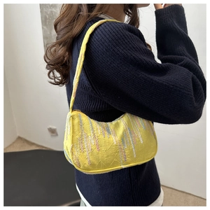 Detail of vibrant yellow shoulder bag featuring multi-colored fringe and woven embroidery