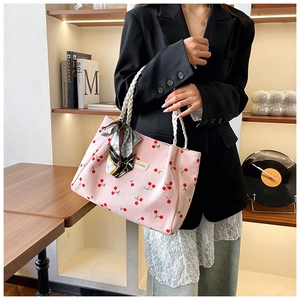 Pink corduroy tote bag with cherry print and woven rope handle shown on woman's arm