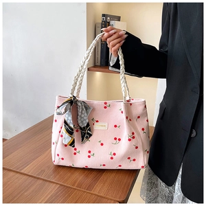 Detail of pink corduroy tote bag with cherry print, woven handle and silk scarf accessory