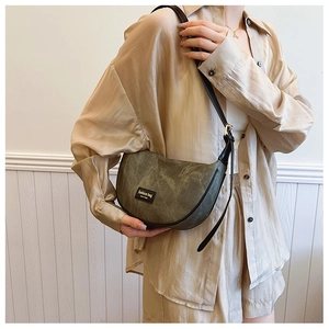 Macro detail of retro crescent shoulder bag featuring olive suede texture and leather logo