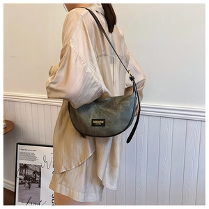 Detail of vintage green half-moon crossbody bag with textured fabric and fashion logo