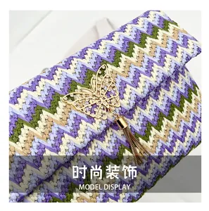 Detail of woven straw clutch with colorful zigzag patterns and a golden butterfly tassel clasp