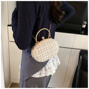 Detail of tweed evening bag featuring woven texture and ornate gold metal handle