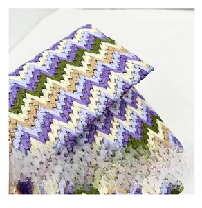 Close-up of woven chevron pattern in purple and green with gold pendant detail