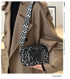 Detail of leopard print camera bag with SM logo and wide woven shoulder strap