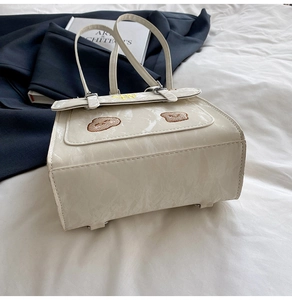 Detail of cream-white backpack with bear embroidery and textured faux leather finish