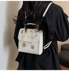 Détails d'un mini sac à dos blanc avec broderies de dessins animés et fini brillant
