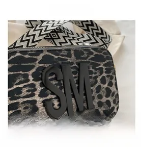 Detail of leopard print camera bag with black 3D logo and zigzag woven shoulder strap