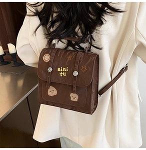 Détail du sac à dos en similicuir marron avec broderies et boucle métallique argentée