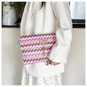Detail of straw woven envelope clutch with gold butterfly buckle and tassels