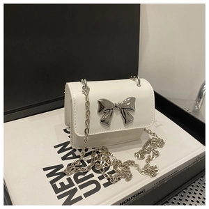 Detail of white leather mini crossbody bag with silver metal bow and chain strap