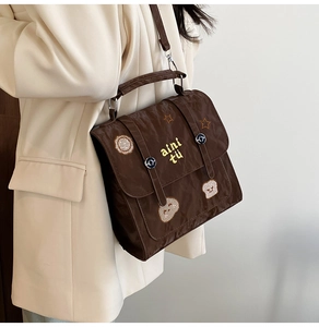 Seitenansicht braune Plissee-Umhängetasche mit Stern-Patches auf beige Sakko