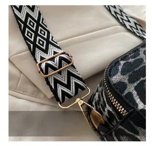 Detail of adjustable gold buckle and woven strap on black leopard texture bag
