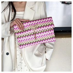 Detail of multi-color woven straw clutch featuring butterfly rhinestone buckle and gold tassels